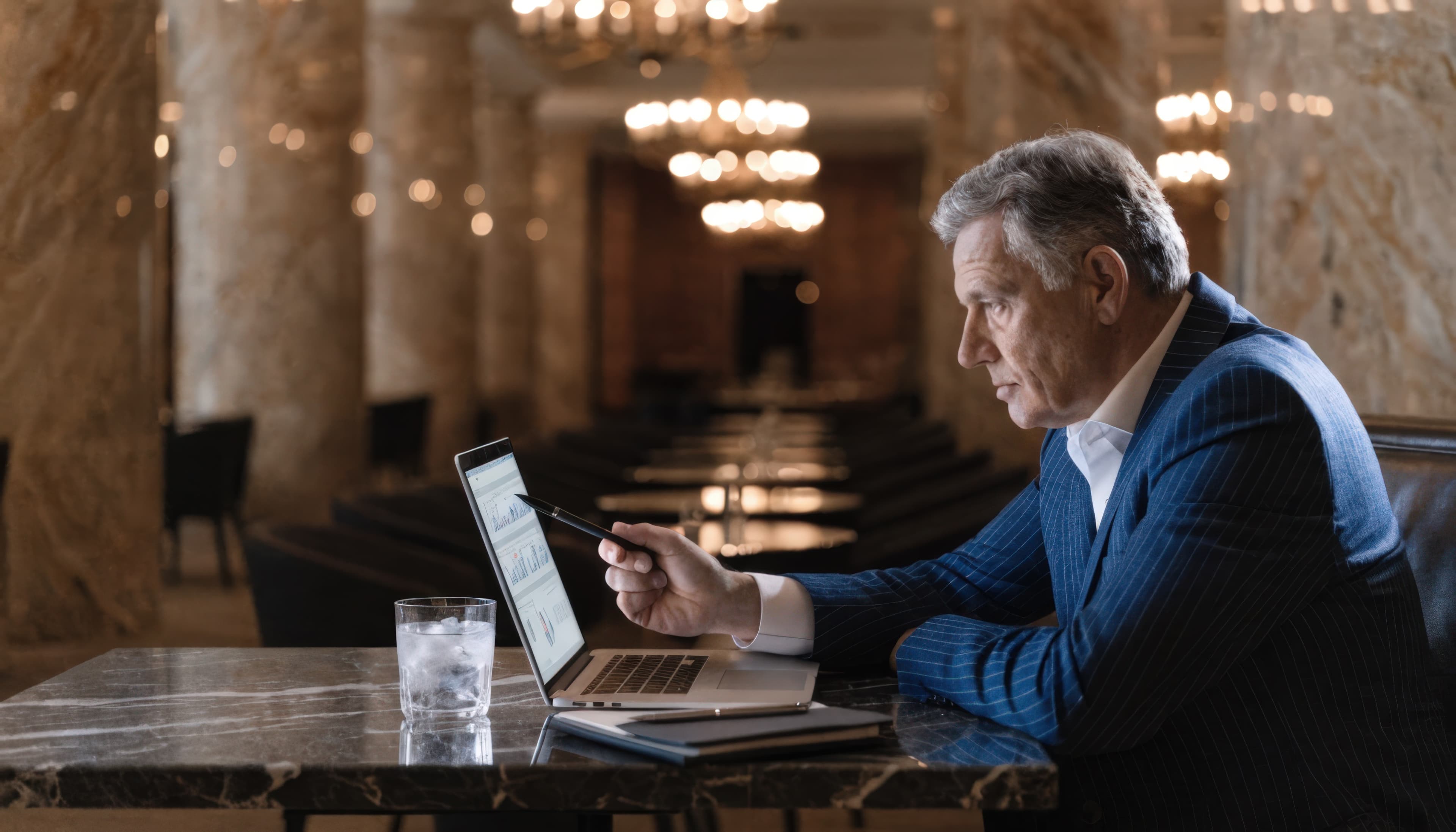 Hotel owner reviewing market intelligence dashboard on a laptop in a marble lobby