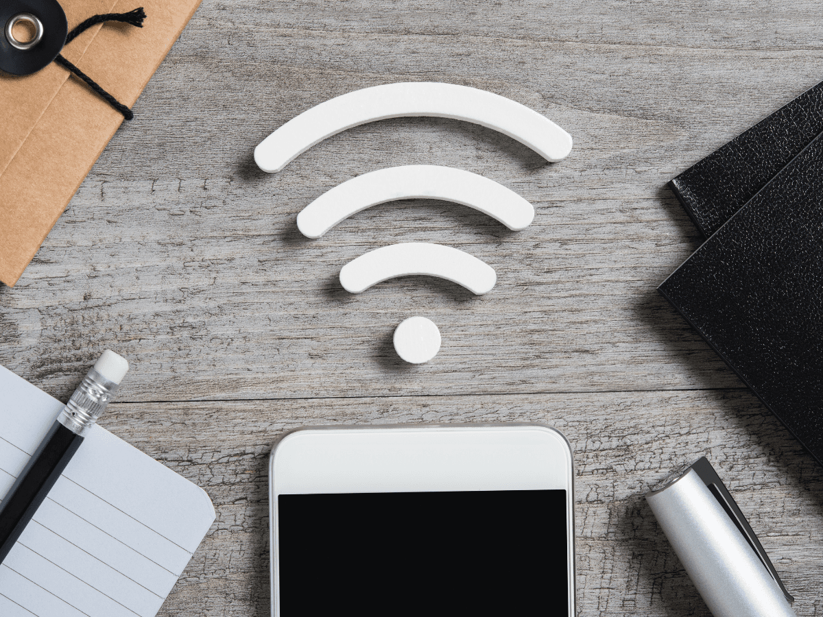 A Wi-Fi symbol on a desk beside a phone, notebook, and keys